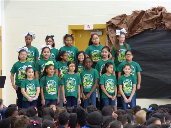 Sawyer Road Chorus students performing songs from How the Grinch Stole Christmas to an assembly of students